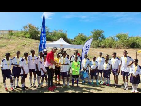 Watsonton Primary School’s football captain Davin McKay (centre, right) receiving the Insports Clarendon Primary Schools football trophy from Insports’ Officer Sylvester Campbell, after Watsonton defeated Effortville Primary School 1-0 in the recent final.