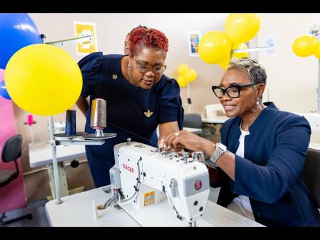 State Minister in the Ministry of National Security and Peace, Hon Juliet Cuthbert-Flynn (right), is being assisted by Chief Technical Director in the Ministry, Shauna Trowers, with threading a sewing machine in the new sewing lab at the South Camp Juvenile Correctional and Remand Centre in Kingston, at the official opening of the facility recently.

