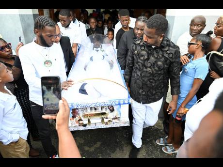 Pall-bearers carry the casket containing the body of Kerrio Pinnock from the Regent Street Seventh-day Adventist Church in Kingston yesterday.