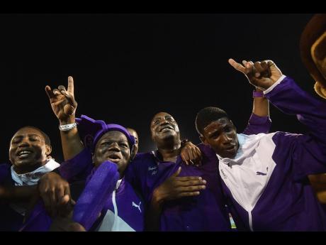 Kingston College Principal Dave Myrie (centre) celebrates with athletes after winning the 2019 Boys’ Championships.