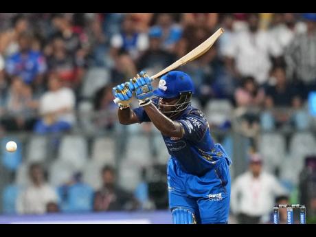 Mumbai Indians’ West Indian batsman Shefane Rutherford hits a boundary during the Indian Premier League cricket match between Mumbai Indians and Royal Challengers Bengaluru, in Mumbai , India, yesterday. Rutherford hit nine sixes in an unbeaten 31-ball 71.