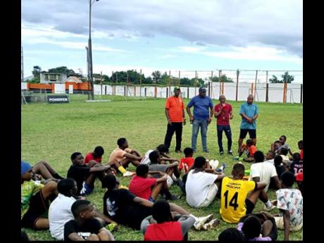 Members of the Jamaica Diaspora Football Association (JDFA), Colonel Bruce Bartlett, Raymond Anderson, coach Calvin Salmon and president Michael Barnes address young footballers at the JDFA grassroots camp at the Edward Seaga Sports Complex recently.