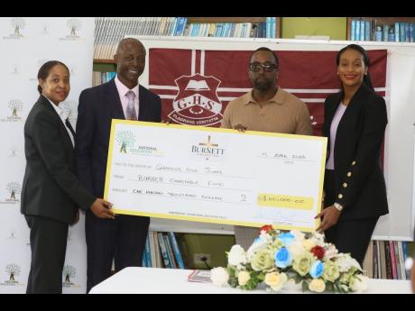 Howard Edwards (second left), acting principal, Glenmuir High School, collects  a cheque valued at US$100,000 from Dale Burnett of Burnett Charitable Fund in partnership with the National Education Trust. They are joined by Rhoda Moy Crawford (right), minister of state, Ministry of Education, Youth, Skills and Information; and Keisha Johnson, director, donor and partnership management at the National Education Trust. The presentation was made during a ceremony held at the school on Monday. 