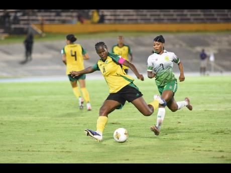 Jamaica’s Khadija Shaw strikes at goal during a Concacaf W Qualifier against Guyana at the National Stadium on Saturday night. Chasing back is Guyana’s Otesha Charles.