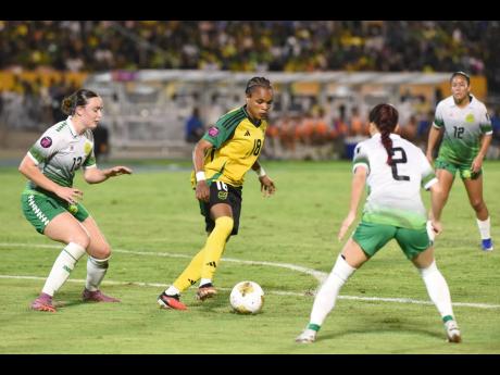 Reggae Girl Trudi Carter (centre) attempts to turn away from the attentions of Guyana’s Heike Clarke (left) and Rylee Traicoff during their Concacaf W Qualifier inside the National Stadium on Saturday.
