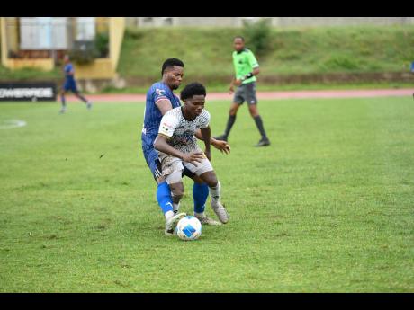 Kimarley Scott of Cavalier FC (front) is tackled by Andrew Vanzie of Spanish Town Police FC during the Jamaica Premier League football match at Stadium East on Monday. Cavalier won 3-0.