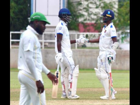 Barbados Pride batsmen Kevin Wickham (centre) and Kraigg Brathwaite meet mid-pitch during their century stand against the Jamaica Scorpions on day three of their West Indies Championship match at Sabina Park yesterday. Jamaica Scorpions’ Kirk McKenzie is in the foreground.