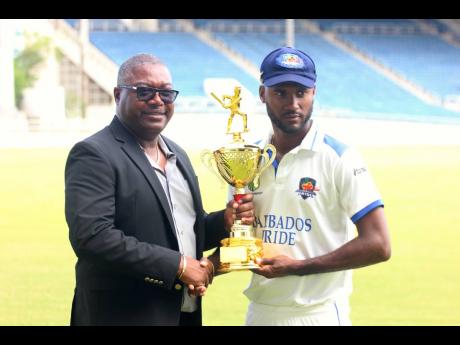 Barbados Pride captain Kragg Brathwaite (right) collects the bilateral series trophy from Jamaica Cricket Association CEO, Courtney Francis at the end of the West Indies Championship match against Jamaica Scorpions at Sabina Park yesterday.