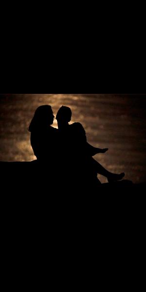 FILE - In this June 27, 2018 file photo, a couple is silhouetted against moonlight reflecting off the Missouri River as they watch the full moon rise beyond downtown buildings in Kansas City, Mo. Money can create stress within a relationship, but talking through expectations and money beliefs can help couples get on the same page. In fact, conflict over money can be healthy, partly because we often partner with people who are our financial opposites.